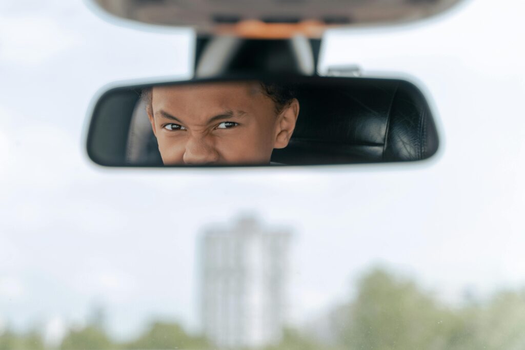 pexels photo 9518246 9518246 A teenager practices driving, seen concentrating in a car's rearview mirror.